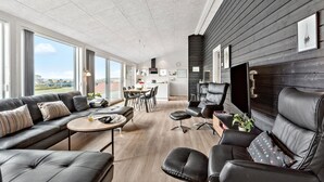 A modern living room with leather sofas, a dining area, and a kitchen.