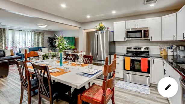 A modern kitchen with white cabinets, stainless steel appliances, and a dining area with a table set for four. - conveniently located home is perfect for families and friends , near Hershey ! (Palmyra)