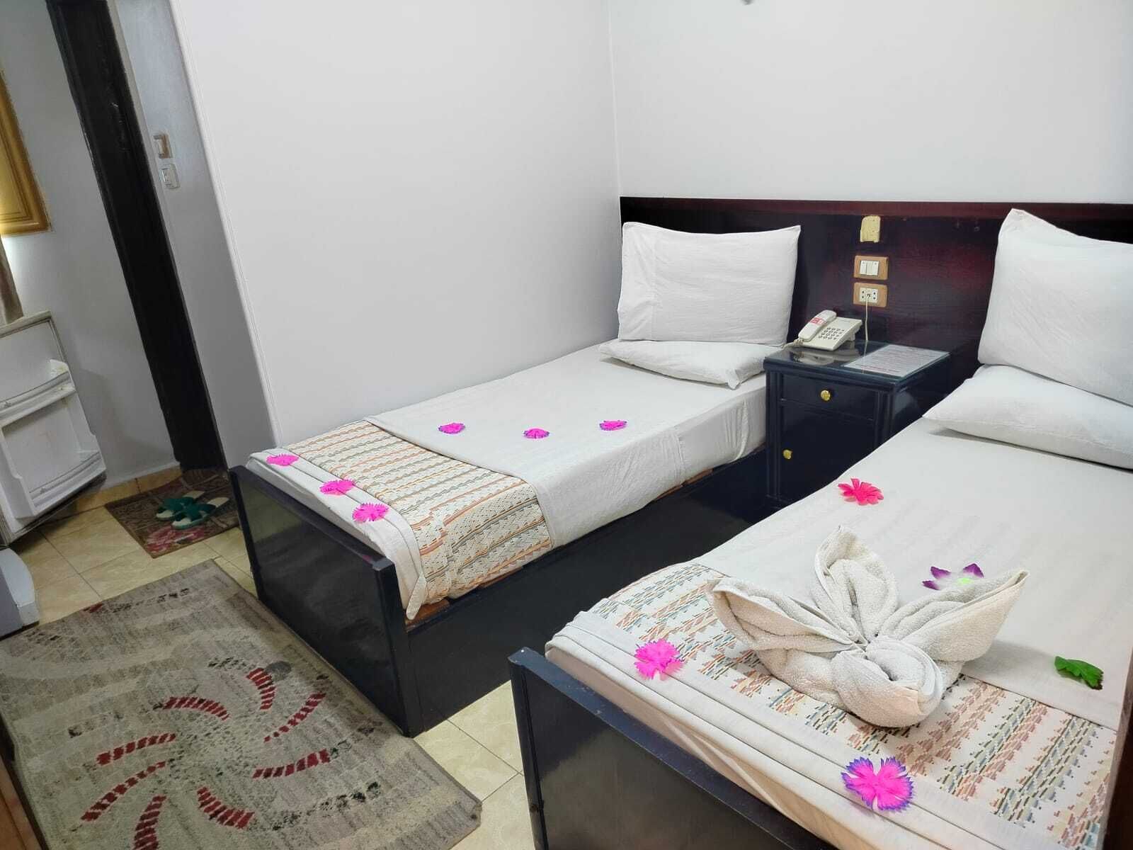 Una habitación de hotel con dos camas, una mesita de noche, un escritorio y una silla.