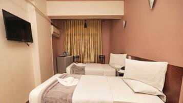 Habitació d'hotel amb dos llits, una televisió penjada a la paret i una finestra amb cortines.