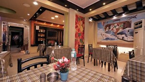 A dining area with checkered tablecloths, a large mural of buses, and a modern kitchen in the background.