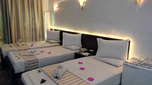 A hotel room with two single beds, each with a pillow, a bedside table with a phone, and a small refrigerator.