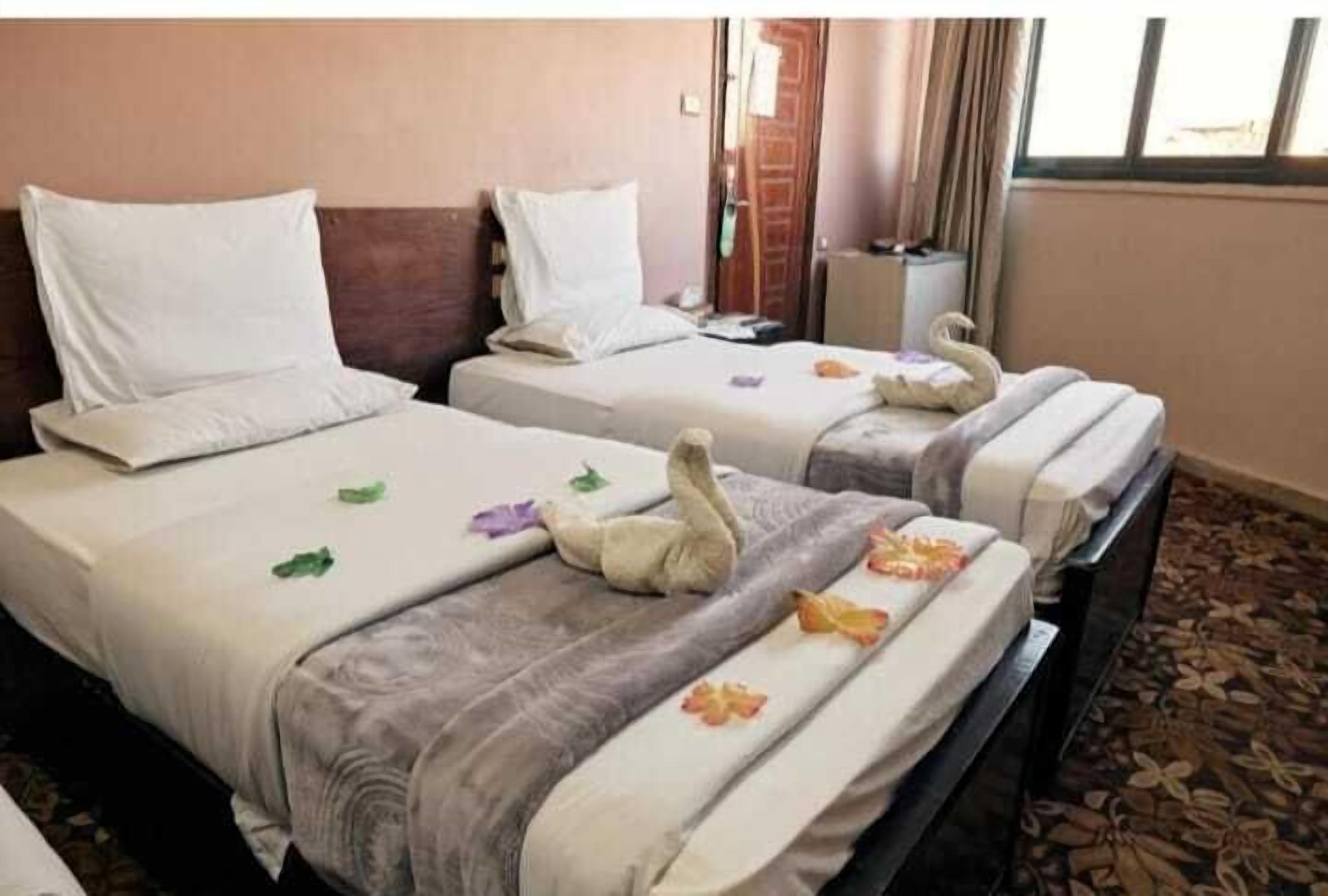 Due letti d'albergo con asciugamani e cuscini decorati a forma di cigno.