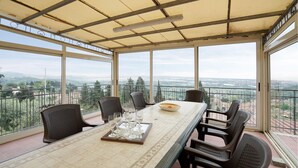 Un comedor con una mesa larga, seis sillas y vistas a un paisaje montañoso a través de amplios ventanales.