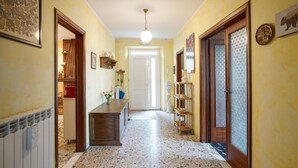 Un pasillo con piso de terrazo, puertas de madera y una puerta blanca al final.