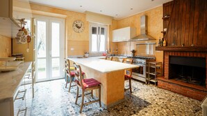Una cocina con una isla grande, estufa a gas, chimenea de ladrillo y ventana con persianas.