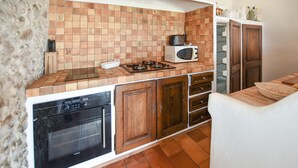 Una cocina con salpicadero de azulejos, estufa a gas, microondas y armarios de madera.