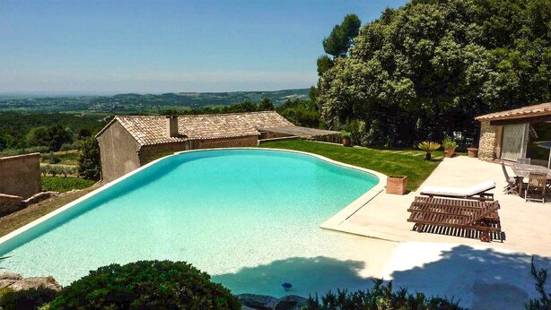 Una piscina con agua cristalina, rodeada de un patio con sillas de descanso y una mesa.