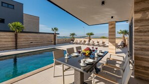 A poolside dining area with a table set for four, overlooking a pool and a scenic view. - Beautiful home in Privlaka (Privlaka)