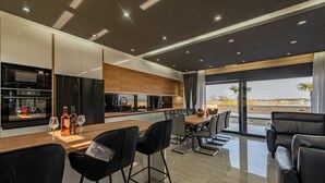 A modern kitchen with a central island, bar stools, and a dining area with a view. - Beautiful home in Privlaka (Privlaka)