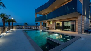 A modern two-story building with a swimming pool, outdoor seating, and a view of the mountains. - Beautiful home in Privlaka (Privlaka)