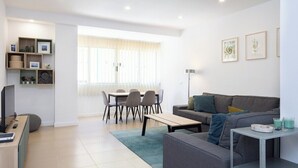 A modern living room with a grey sofa, a coffee table, a TV, and a dining area with chairs and a table. - Home2Book Pleasant & Design Apt Santa Cruz Center (Santa Cruz de Tenerife)