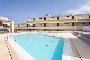 Une piscine à l’eau d’un bleu cristallin, entourée d’une terrasse carrelée.