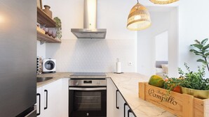A modern kitchen with white cabinetry, a built-in oven, a stainless steel range hood, and a wooden fruit crate on the counter. - Home2Book Stylish Apt Terrace Las Américas (Playa de la Américas)