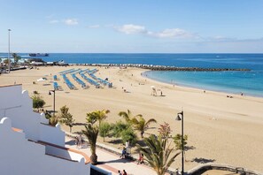 A beach with rows of blue umbrellas, a sandy shore, and a clear blue sea. - Home2Book Stylish Apt Terrace Las Américas (Playa de la Américas)
