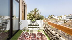 A balcony with a table and chairs, a potted plant, and a view of palm trees and buildings. - Home2Book Stylish Apt Terrace Las Américas (Playa de la Américas)