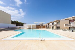 A swimming pool with a clear blue water surface, surrounded by a tiled deck area.