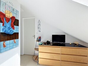 A room with a wooden dresser, a television on top, and a painting on the wall. - Entre Ciel et Mer - Vue Mer - 3 CH & Parking (Bray-Dunes)