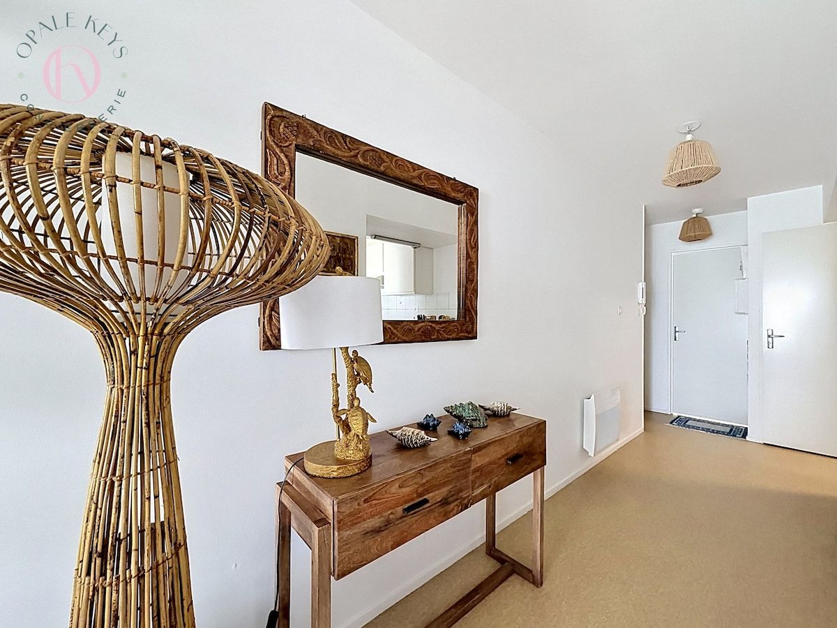 Un couloir avec une console en bois, un miroir et un lampadaire à pied en osier.