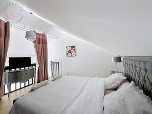 A bedroom with a bed, a bedside table, a lamp, a television, and a window with curtains. - Entre Ciel et Mer - Vue Mer - 3 CH & Parking (Bray-Dunes)