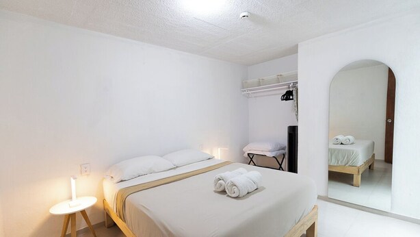A minimalist bedroom with a bed, bedside table, and a mirror. - Apartment with parking in Tlaquepaque Pueblo Mágico (Guadalajara)