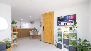 A modern reception area with a wooden door, a reception desk, a TV displaying a streaming service, and potted plants. - Apartment with parking in Tlaquepaque Pueblo Mágico (Guadalajara)