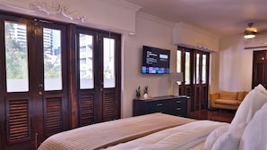 Habitación de hotel con una cama grande, un televisor montado en la pared, un escritorio con lámpara y vistas al exterior a través de las ventanas.