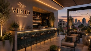 Un bar en la azotea llamado 'VENTO', con barra, zona de estar y vistas al horizonte de la ciudad.