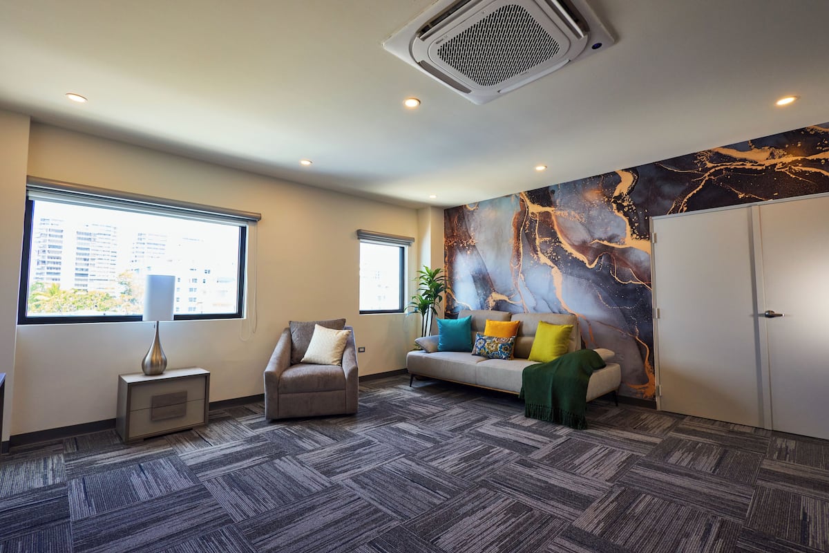Een moderne hotelkamer met een bank, fauteuil en een groot raam.