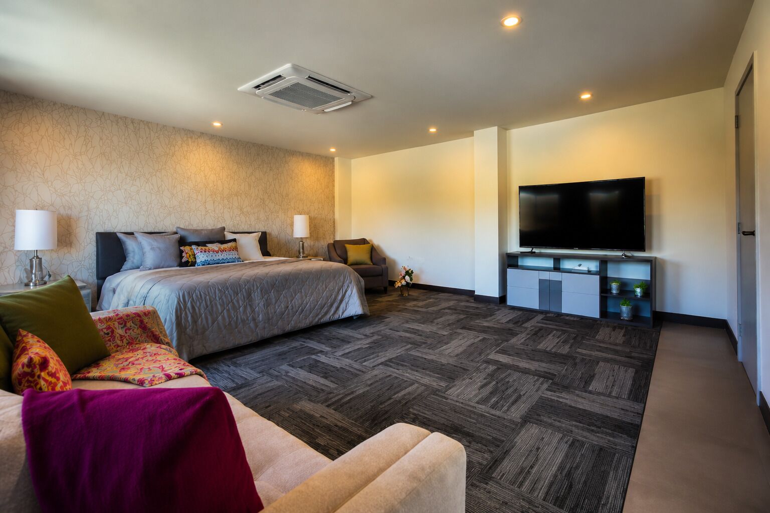 A hotel room with a bed, a sofa, a TV, and a small table.