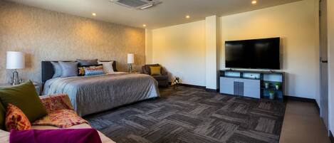 A hotel room with a bed, a sofa, a TV, and a small table.