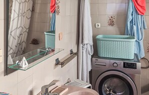 A compact bathroom with a washing machine, a glass shelf, and a mirror. - 3 bedroom awesome home in Villanueva del Rey (Villanueva del Rey)