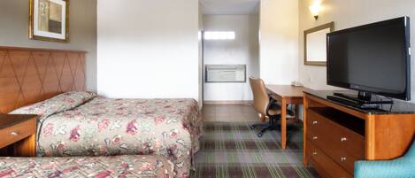 A hotel room with a bed, a desk with a chair, a television, and a dresser.