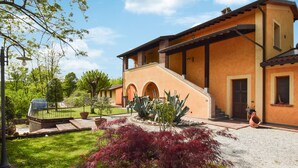 A two-story building with a central staircase, arched doorways, and a garden with red-leafed plants. - Cozy apartment in Santa Maria a Monte (Santa Maria a Monte)