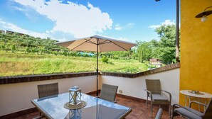A balcony with a glass table, wicker chairs, and a large umbrella. - Cozy apartment in Santa Maria a Monte (Santa Maria a Monte)