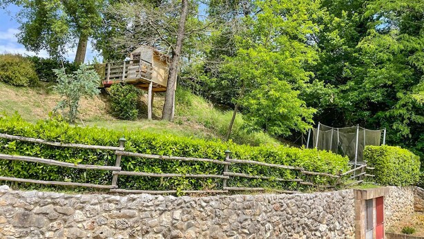 A stone wall with a wooden fence, a treehouse, and a red door. - Cozy apartment in Santa Maria a Monte (Santa Maria a Monte)