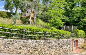 A stone wall with a wooden fence, a treehouse, and a red door. - Cozy apartment in Santa Maria a Monte (Santa Maria a Monte)