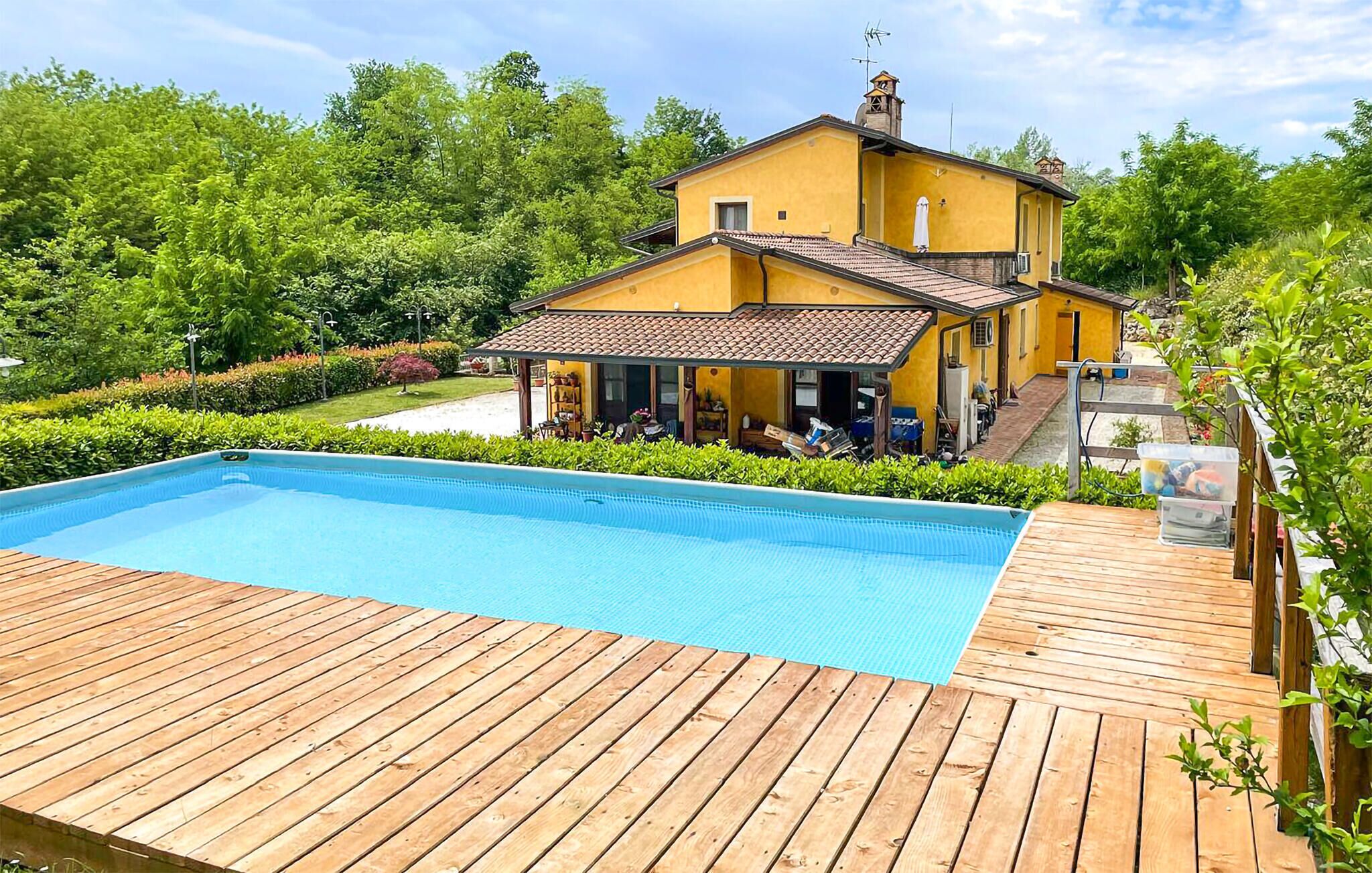 Una casa amarilla con piscina y terraza de madera.