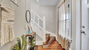 Un escalier avec des finitions en bois, une décoration murale en macramé et une plante en pot.
