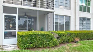 A modern building with a covered entrance, large windows, and neatly trimmed hedges. - Golf/Water View Condo
 (Sarasota)