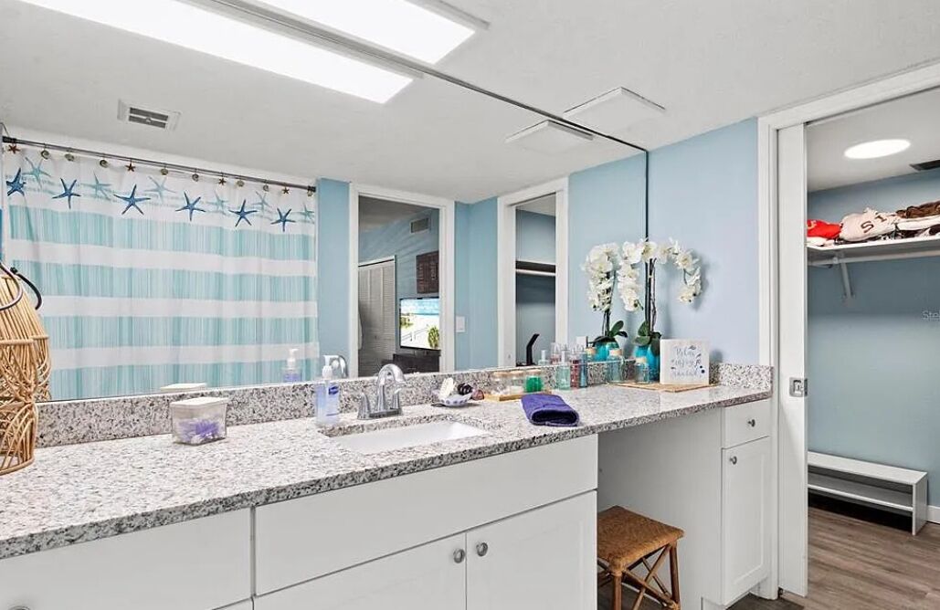 A modern bathroom with a large mirror, a shower curtain with star patterns, and a vanity with a sink and countertop.