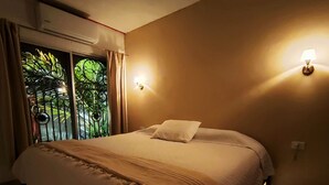 A bedroom with a bed, curtains, and a wall-mounted light fixture. - Villa Colonial en el Centro con Alberca (Mérida)