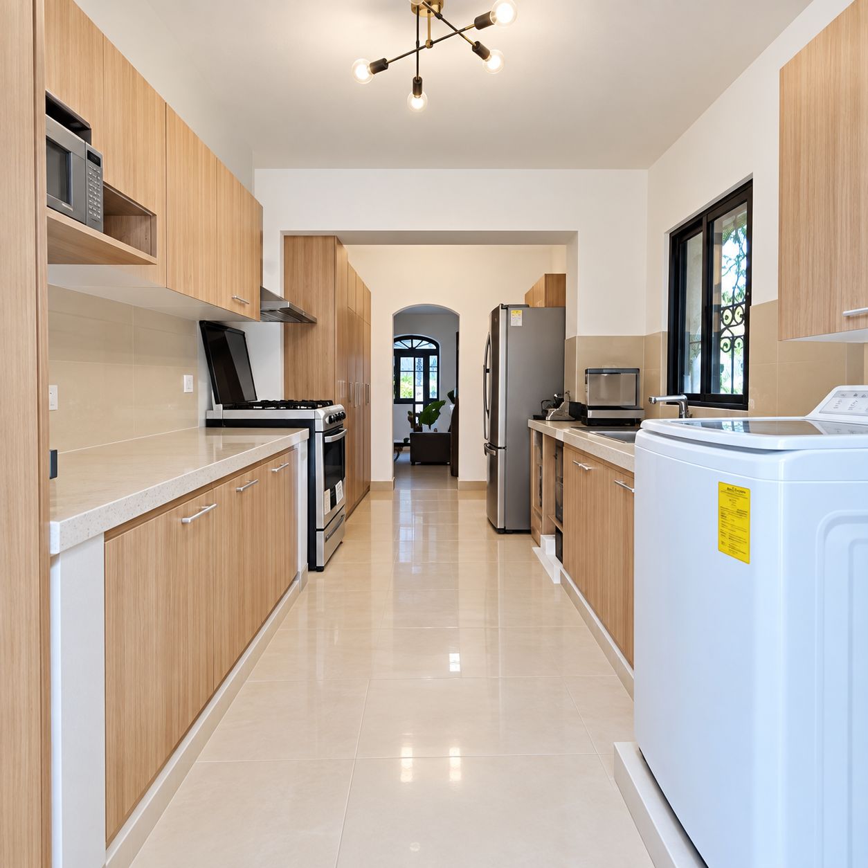 A modern kitchen with wooden cabinets, a stainless steel refrigerator, a built-in oven, and a washing machine.