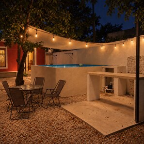 Eine Außenpatio-Terrasse mit Pool, Sitzgelegenheiten und Lichterketten.