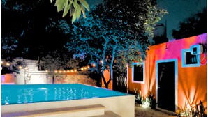 A swimming pool with steps leading up to it, surrounded by trees and a building with a door and window. - Villa Colonial en el Centro con Alberca (Mérida)