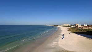 A beach with a clear view of the ocean, a sandy shore, and a row of buildings along the coastline. - Beachfront Condo - 2-Bedroom - Luxury - Directly on Crescent Beach (Siesta Key)