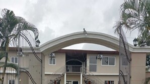 A gated entrance to a two-story building with a central staircase leading to the entrance. - Hotel Mar y Mar (San Marcos)
