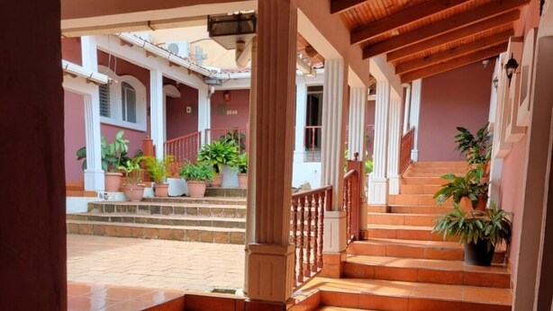 A covered outdoor area with tiled flooring, wooden columns, and steps leading to a building entrance. - Hotel Mar y Mar (San Marcos)