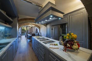 A modern kitchen with a marble countertop, stainless steel appliances, and a central island with fresh produce.