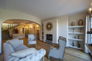 A living room with a fireplace, a staircase, and a bookshelf with decorative items.